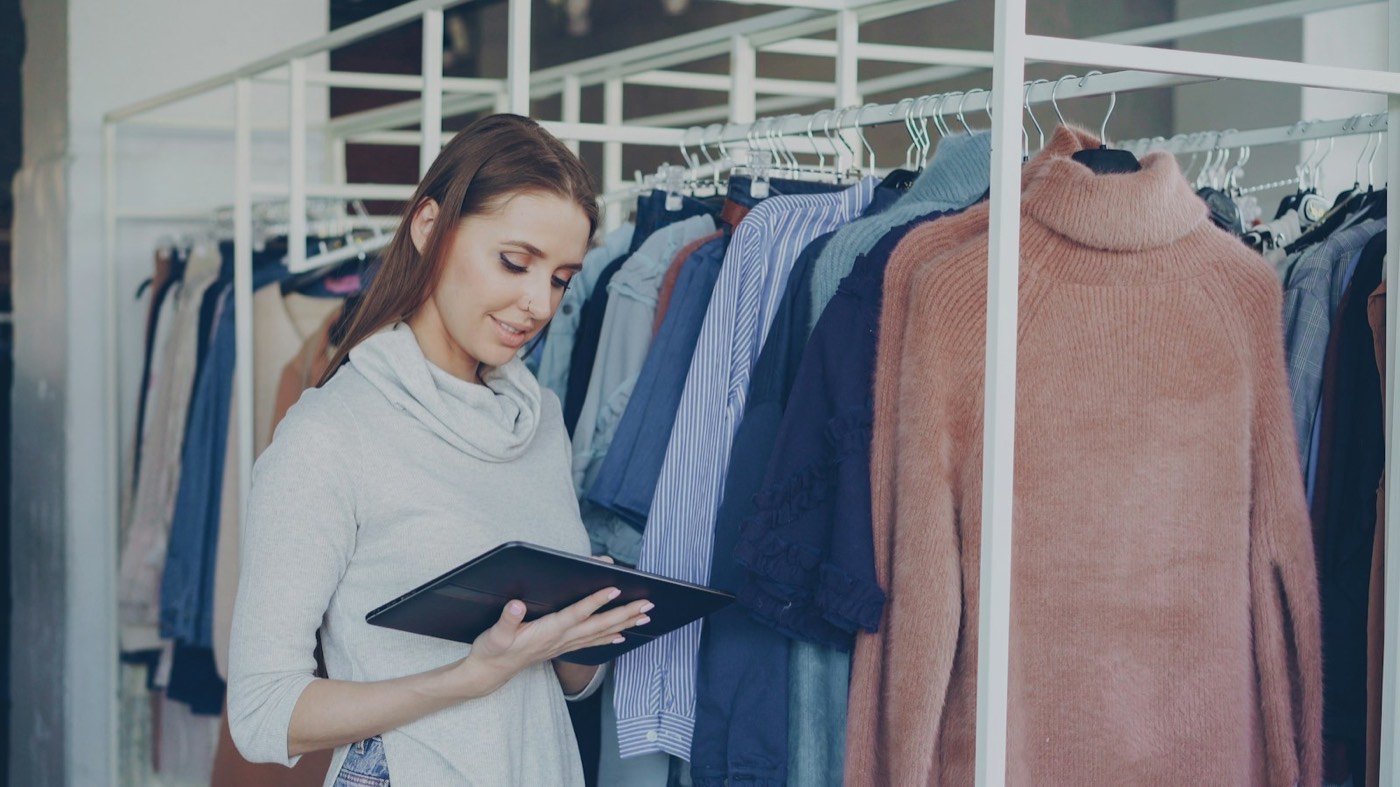 Une commerçante consulte une tablette dans sa boutique
